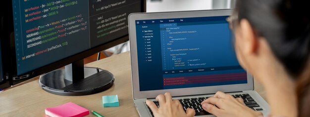 Imagen recortada de una desarrolladora web femenina codificando en una computadora portátil mientras la computadora muestra el programa y el código de software en una oficina moderna Cerrar la mano de una mujer de negocios enfocada en los datos de análisis