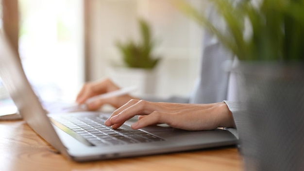 Imagen recortada Empresaria mano escribiendo en el teclado de la computadora portátil portátil