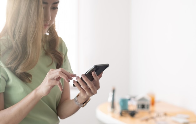 Imagen recortada de encantadora mujer asiática con teléfono móvil.