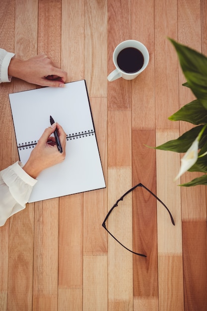 Imagen recortada de la escritura de la mujer en el bloc de notas