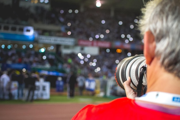 Foto imagen recortada del fotógrafo de pie con la cámara en el estadio