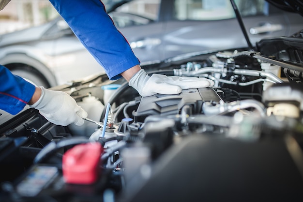 Imagen recortada de guapo mecánico en uniforme está trabajando en el servicio de automóviles. Reparación y mantenimiento de automóviles.