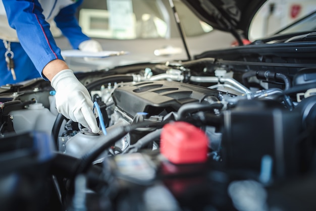 Imagen recortada de guapo mecánico en uniforme está trabajando en el servicio de automóviles. Reparación y mantenimiento de automóviles.