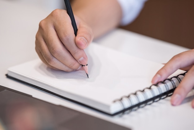 Imagen recortada de hombre escribiendo en el cuaderno mientras trabajaba en la oficina