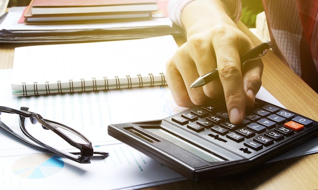 Foto imagen recortada de un hombre de negocios usando una calculadora en el escritorio