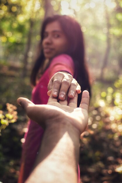 Foto imagen recortada de un hombre sosteniendo la mano de una mujer en el bosque