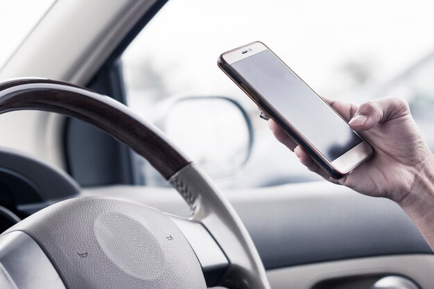 Imagen recortada de un hombre usando un teléfono móvil mientras conduce un automóvil