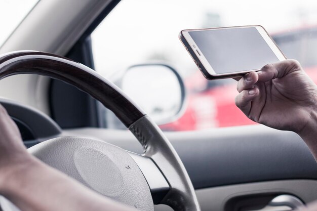 Imagen recortada de un hombre usando un teléfono móvil mientras conduce un automóvil