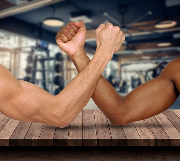 Imagen recortada de hombres flexionando los músculos en la mesa en el gimnasio