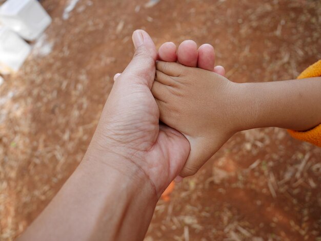 Imagen recortada de la madre sosteniendo las manos del niño
