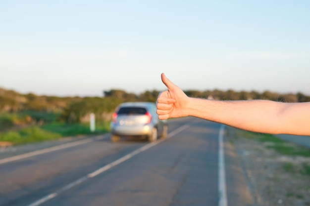 Foto imagen recortada de la mano en el coche contra el cielo