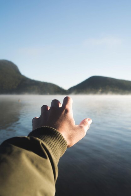 Foto imagen recortada de una mano contra el mar