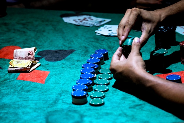 Imagen recortada de una mano jugando fichas de póquer en la mesa