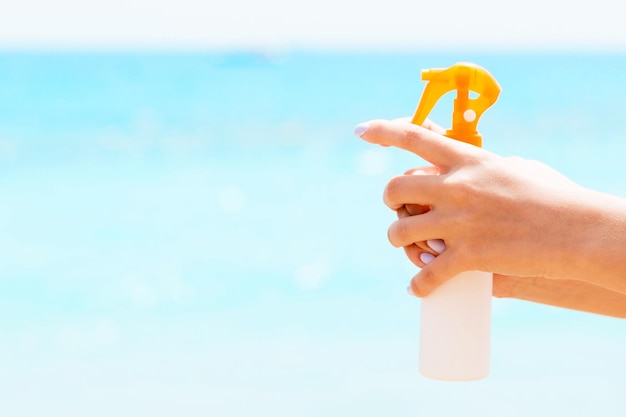 Imagen recortada de la mano de una mujer sosteniendo spray protector solar en el fondo del mar