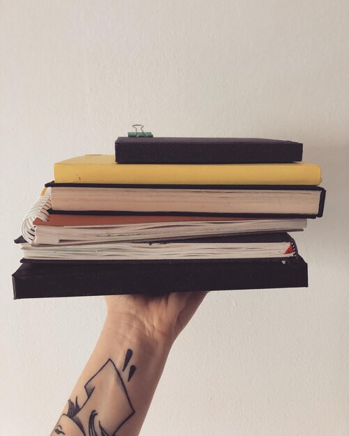 Foto imagen recortada de una mano sosteniendo un libro contra la pared