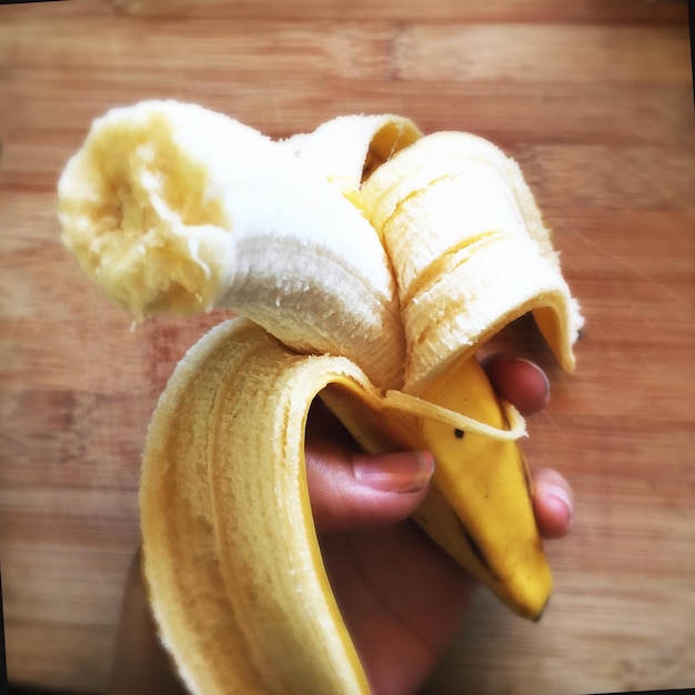 Foto imagen recortada de una mano sosteniendo un plátano
