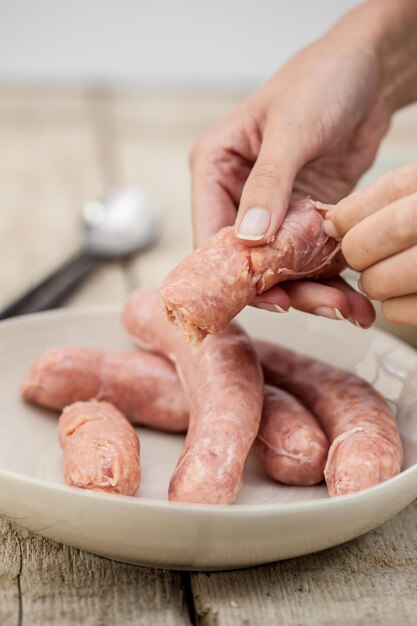 Foto imagen recortada de una mano sosteniendo una salchicha pelada en un cuenco