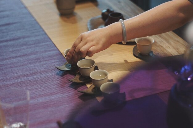 Foto imagen recortada de la mano vertiendo la taza de café en la mesa