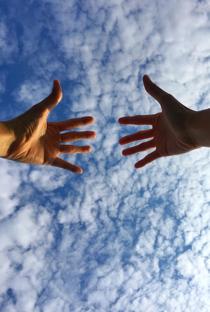 Foto imagen recortada de manos contra un cielo nublado