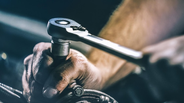 Imagen recortada de un mecánico reparando el motor de un automóvil