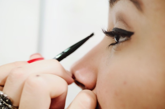 Imagen recortada de una mujer aplicando eyeliner