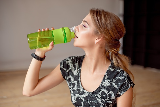 Foto imagen recortada de mujer deportiva con botella de agua.