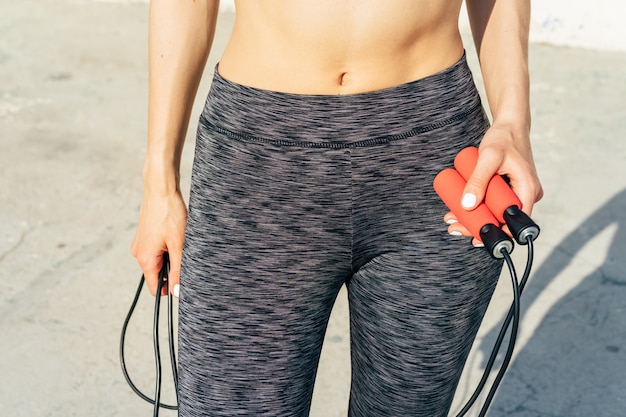 Imagen recortada de mujer deportiva con una cuerda de saltar en sus manos