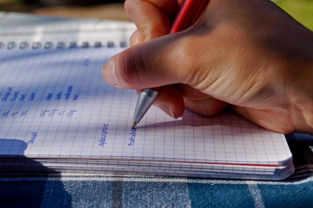 Foto imagen recortada de una mujer escribiendo en un libro en la mesa