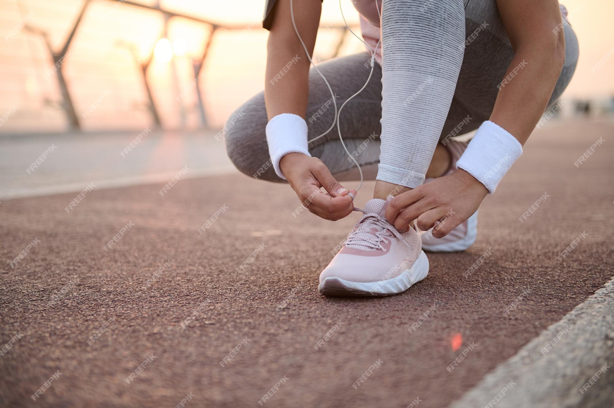 Imagen recortada de una mujer fitness atando cordones de zapatos zapatillas deporte y preparándose para correr por la mañana y hacer ejercicio deportivo al aire libre en una cinta de