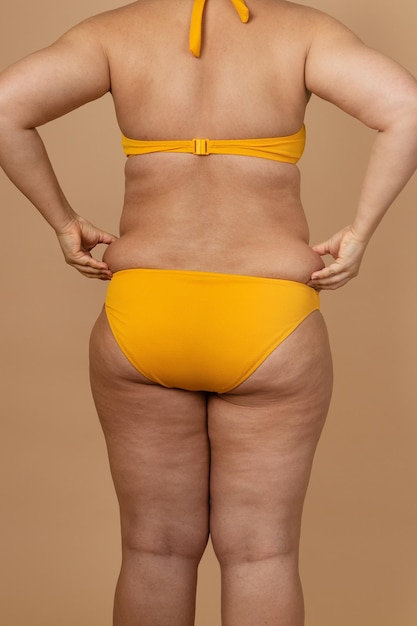 Imagen recortada de mujer gorda con sobrepeso con obesidad exceso de grasa en traje de baño amarillo