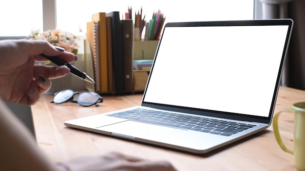 Imagen recortada de una mujer independiente sosteniendo un lápiz y usando una computadora portátil