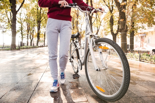 Imagen recortada de mujer joven caminando con su bicicleta en la calle