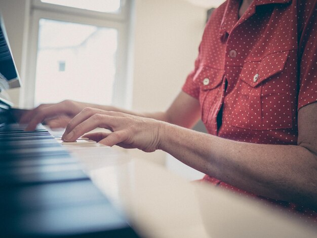 Imagen recortada de una mujer joven tocando el piano en casa