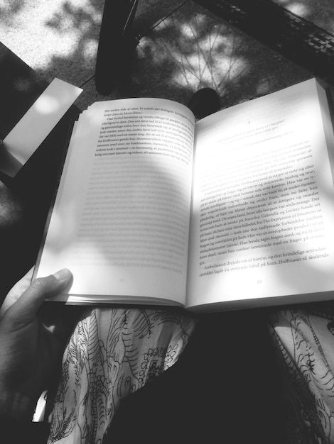 Imagen recortada de una mujer leyendo un libro mientras está sentada al aire libre