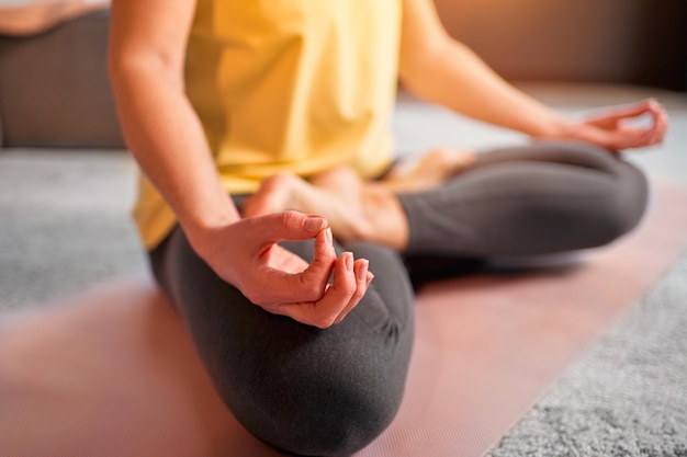 Imagen recortada de una mujer practicando yoga y meditación en postura de loto.