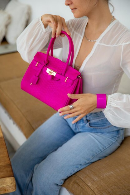 Imagen recortada de una mujer que sostiene una pequeña bolsa de compras rosa con ropa informal