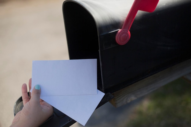 Foto imagen recortada de una mujer quitando una carta del buzón