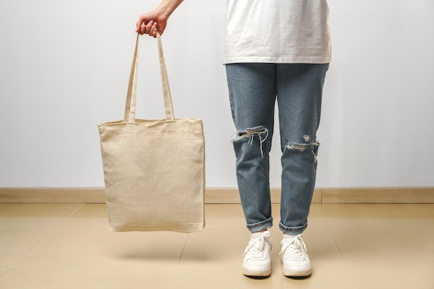 Imagen recortada de mujer sosteniendo bolsa de compras beige en estudio