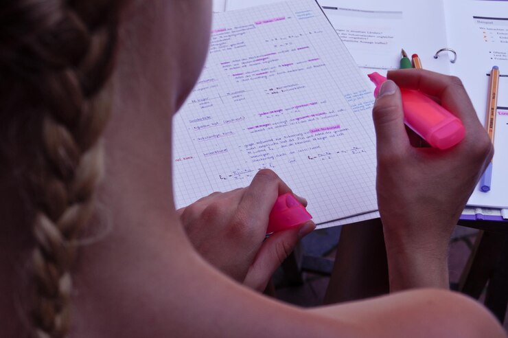 Foto imagen recortada de una mujer sosteniendo un marcador rosa con documentos en la mesa