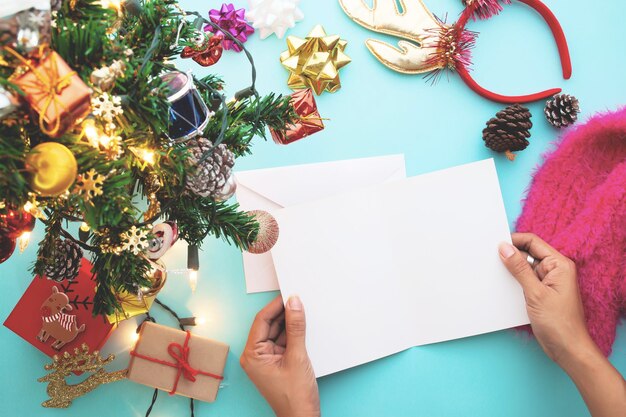 Foto imagen recortada de una mujer sosteniendo una tarjeta de felicitación con varios objetos en la mesa