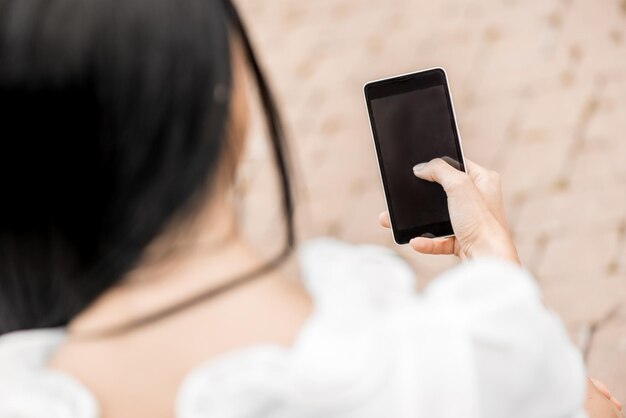 Imagen recortada de mujer sosteniendo teléfono inteligente con pantalla en blanco