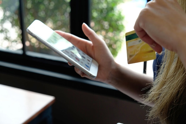Foto imagen recortada de una mujer con tarjeta de crédito y usando el teléfono