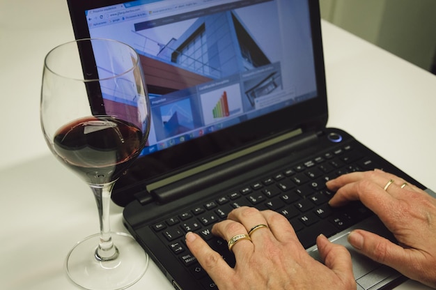 Foto imagen recortada de una mujer usando una computadora portátil en la mesa en casa