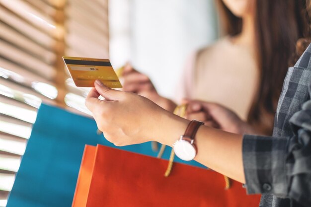 Imagen recortada de mujeres con bolsas de compras y tarjetas de crédito