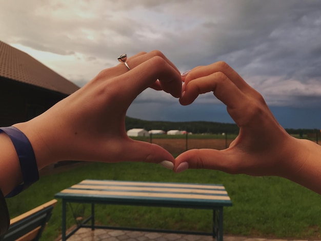 Foto imagen recortada de mujeres haciendo forma de corazón con las manos contra el cielo