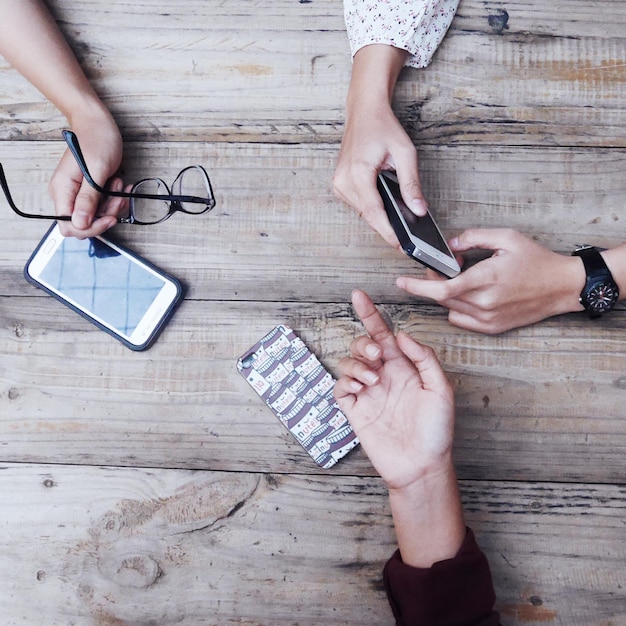 Imagen recortada de mujeres con teléfonos móviles en la mesa