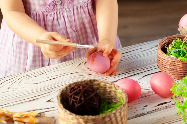 Imagen recortada de una niña pintando huevos para Pascua