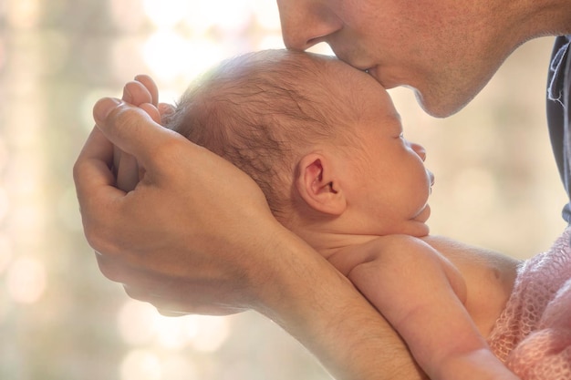 Imagen recortada de un padre besando la frente de su bebé al aire libre