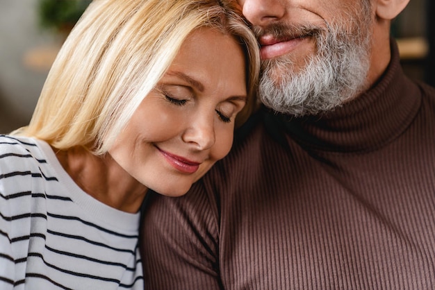 Imagen recortada de una pareja de mediana edad en casa relajándose en el sofá enamorada