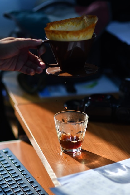 Imagen recortada de una persona filtrando café en un escritorio en la oficina
